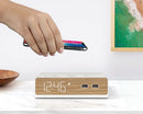 Person placing cell phone on top of the Station W All Inclusive Alarm Clock for wireless charging.